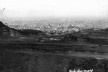 Fotografia tirada a partir da Serra do Curral que mostra mina de minério de ferro que foi explorada pela Ferrobel até 1979. Observa-se no canto superior esquerdo os taludes recortados pela atividade mineraria [Coleção José Góes, APM, 1977.]