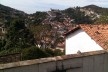 Casa com muro; ao fundo, caminho serpenteante na encosta<br />Foto Abilio Guerra 