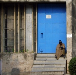 Homem sentado diante de prédio da universidade<br />Foto de Denise Teixeira e Luís Barbieri 