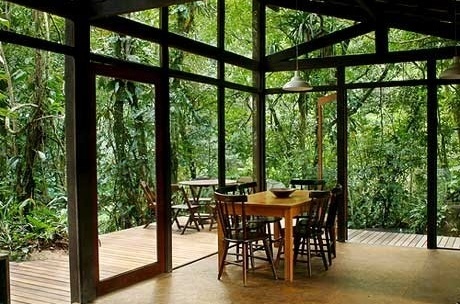 Vista interna do módulo social do ambiente de refeições com o fundo envidraçado que promove a integração do espaço interno com a mata do entorno<br />Imagem dos autores do projeto 