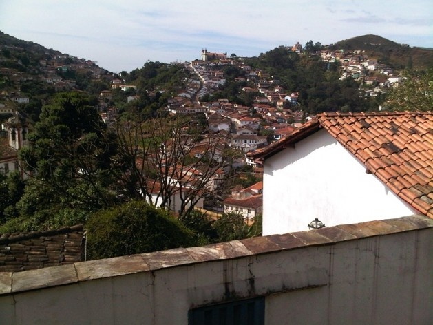 Casa com muro; ao fundo, caminho serpenteante na encosta<br />Foto Abilio Guerra 