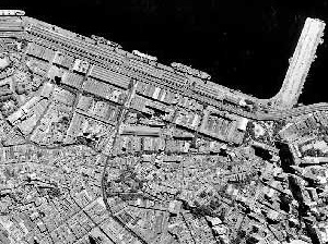 Figura 1 – Foto aérea (geral e zoom) da área portuária permitindo perceber o tecido urbano na região mais elevada, como ocupação predominante do século XIX e as áreas aterradas no início do século XX, ocupadas pelos galpões industriais [Acervo IPLAN-RIO]