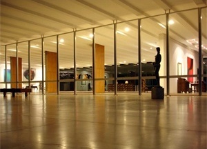 A total transparência entre a varanda, a Sala Portinari, a Sala Duas Épocas é duplicada com o espelhamento pela superfície de vidros escuros. O pilares, revestidos em madeira, permanecem como índices espaciais que se articulam com os planos das paredes<br />Foto Eduardo Rossetti, 2008 