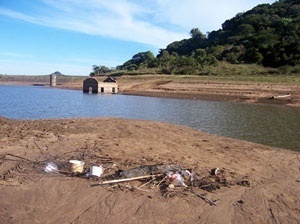 Vista parcial da Barragem do DNOS, 8m abaixo do nível normal, onde se observa o acúmulo de lixo no seu interior e a redução das potencialidades ambientais e paisagísticas<br />Foto autores, 2006 