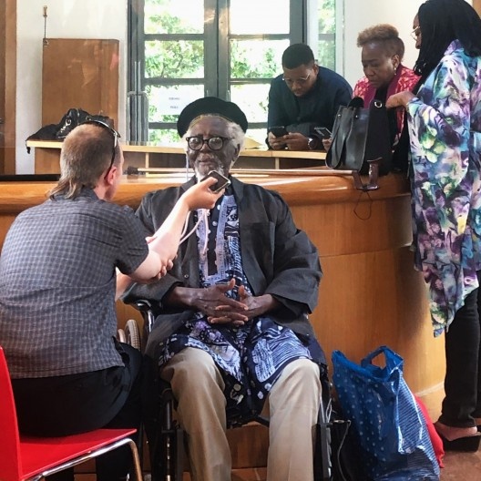 Demas Nwoko sendo entrevistado por Rupert Bickersteth. No fundo o neto Rufus Nwoko, diretor artístico do Nova Cultura de Ibadan<br />Foto Francesco Del Brenna  [Dezeen.com]