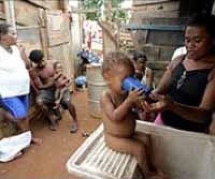 “Na Estrutural, Izailde Souza, de roupa branca, teme sair de casa, com medo de assaltantes. Miriam de Araújo dá a seu filho, Josias, um pouco de água de um tanque”. <br />Foto e texto New York Times 18/01/2004 