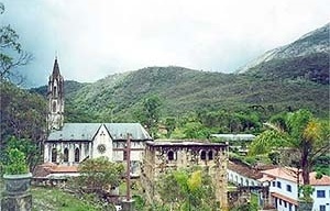 Vista lateral do conjunto, biblioteca, em 1º plano, Igreja, ao fundo e Casa Afonso Pena, à direita, com paredes brancas e janelas azuis<br />Foto Patricia Abreu 
