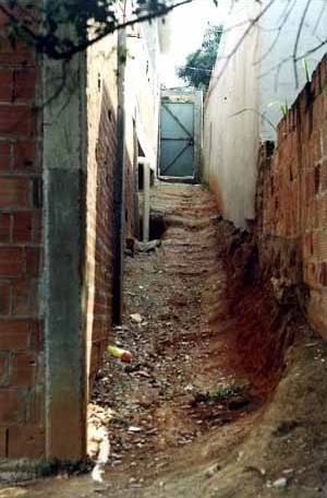 Degradação de encosta pela ação dos fatores controladores, especialmente o runoff. Ao fundo e à esquerda, evidência de cabeceira de voçoroca [Souza, 2001]