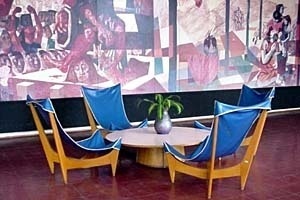 Mobiliário de Joaquim Tenreiro para o Colégio de Cataguases (arquiteto Oscar Niemeyer). Ao fundo, detalhe do painel “Tiradentes” de Cândido Portinari [Arquivo do Autor]